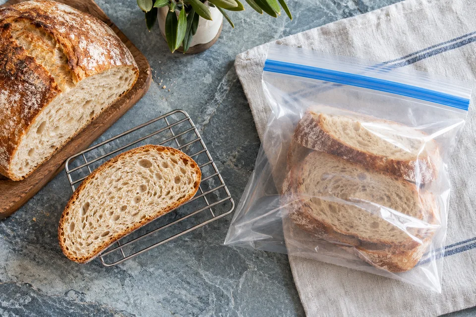 A bread slice beside freezer packaging on a stone surface